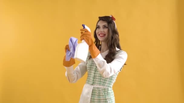 En positiv ung kvinna dansar och tvättar sig i gummihandskar med spray och trasa. — Stockvideo