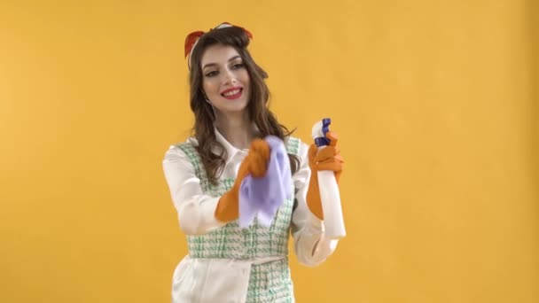 Eine junge Frau wäscht ein unsichtbares Fenster mit Spray und Lappen. Welliges Haar. — Stockvideo