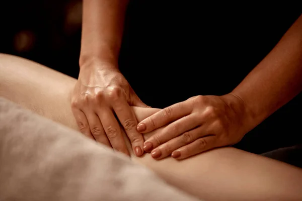 Nenhum rosto de perto das mãos do massagista na perna do cliente. Salão de beleza. — Fotografia de Stock