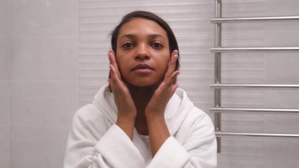 Жінка у ванній вирівнює волосся і дивиться на її обличчя . — стокове відео