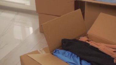 Taşınmak için karton kutularla dolu bir oda. Kamera soldan sağa hareket ediyor..