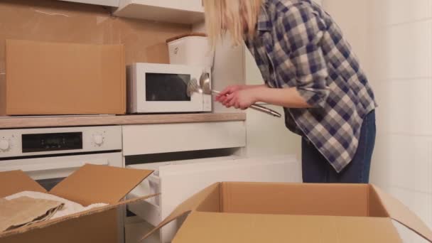Женщина вынимает посуду из картонной коробки. Разберите коробки после перемещения. — стоковое видео