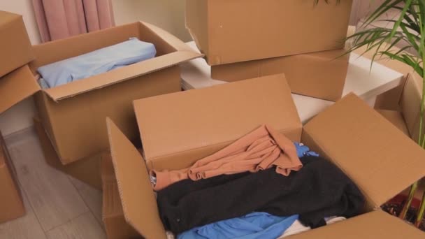 Gros plan d'une boîte de vêtements pour un don. Il y a beaucoup de boîtes en carton. — Video