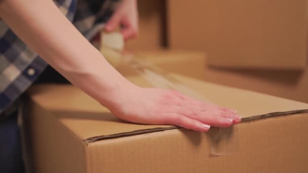 Les mains de femmes couvrent la boîte de déplacement en carton avec du ruban adhésif. Mouvement lent. — Video