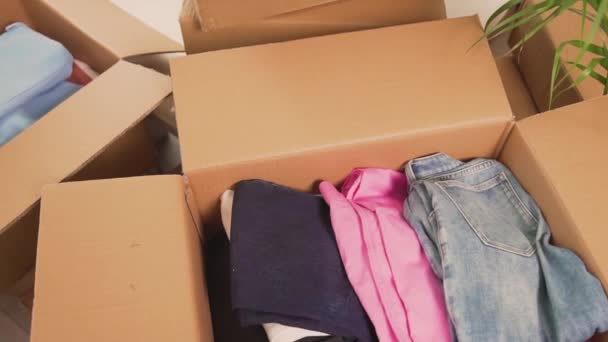 Primer plano de una caja de ropa después de mudarse. Arreglar las cosas después de mudarse. — Vídeos de Stock