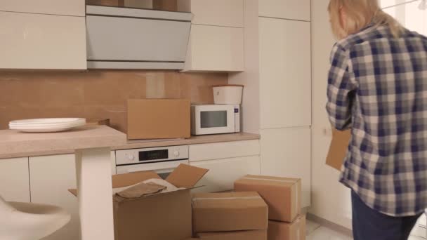 Bir kadın beyaz tabakları karton kutulara koyar. Taşınmaya hazırlanılıyor. — Stok video