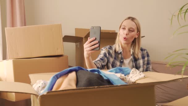 Una donna seduta comunica online tramite collegamento video. Un sacco di scatole di cartone. — Video Stock
