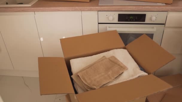In de keuken staat een open kartonnen doos met handdoeken. — Stockvideo