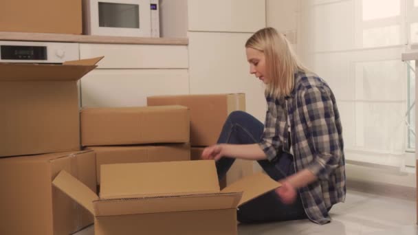 Yerde oturan bir kadın tabakları karton kutulara koyar.. — Stok video