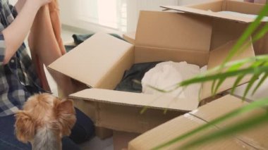 Bir kadın giysilerini karton kutulara koyar, yeni bir eve ya da daireye taşınır..