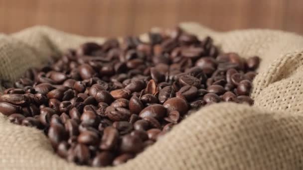 Par le haut, les grains de café sombres tombent dans un éco-sac en toile de jute. — Video