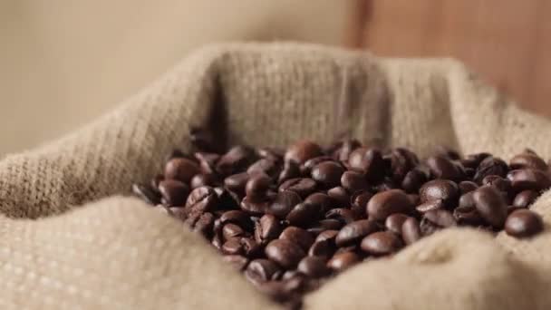 A burlap bag of coffee beans moves around itself. Coffee beans fall from above. — Stock Video