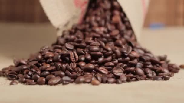 Close-up of roasted coffee beans spilling out of a burlap sack. — Stock Video