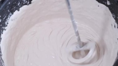 Bir kova çimentoya yakın, kovada çimentoyu karıştırıyor.. 