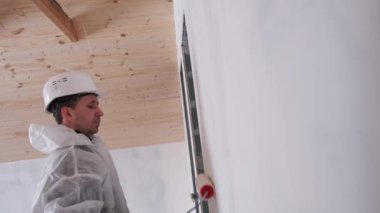 Duvarları boya silindiriyle boyayan bir adam. Evin yenilenmesi..