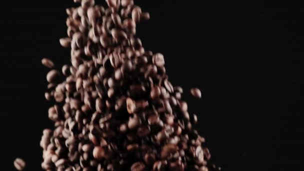 Från botten upp, många svarta rostade kaffebönor flyga upp på en svart bakgrund — Stockvideo