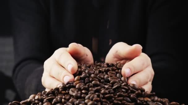Ele pega os grãos de café escuros em suas mãos e os derrama na mesa.. — Vídeo de Stock