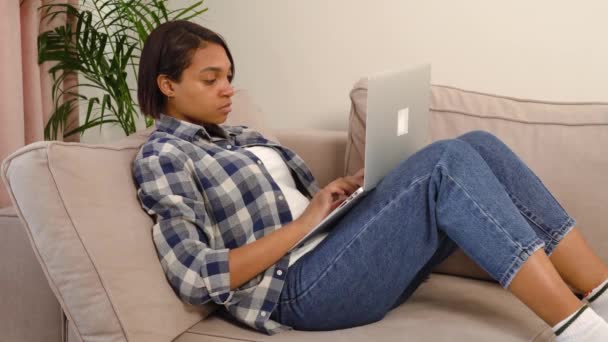 Μια κουρασμένη Αφρο-Αμερικανίδα δακτυλογραφεί μηνύματα στο σπίτι σε ένα λάπτοπ.. — Αρχείο Βίντεο