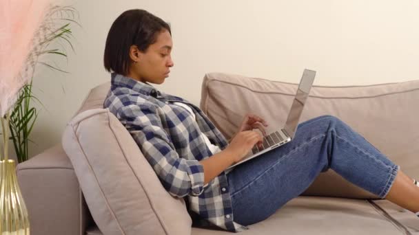 Beautiful dark-skinned woman in casual clothes working at home online. — Video Stock