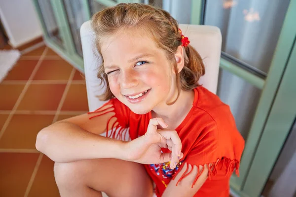 Seorang gadis pirang cantik dengan potongan rambut pendek duduk di kursi, tersenyum Stok Foto Bebas Royalti
