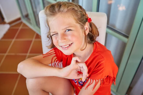 Uma linda garota loira com um corte de cabelo curto está sentada em uma cadeira, sorrindo Fotos De Bancos De Imagens Sem Royalties