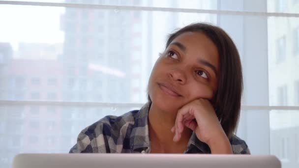 Красивая молодая женщина работает за своим ноутбуком и смотрит мечтательно прочь. — стоковое видео