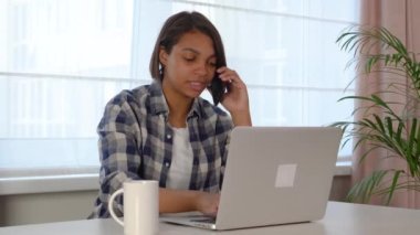 Laptop kullanan genç bir kadın, evdeki bir müşterisiyle internet üzerinden iletişim kuruyor.