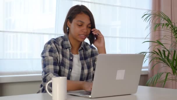 Egy fiatal nő laptopot használ, kommunikál az interneten egy ügyféllel otthon. — Stock videók