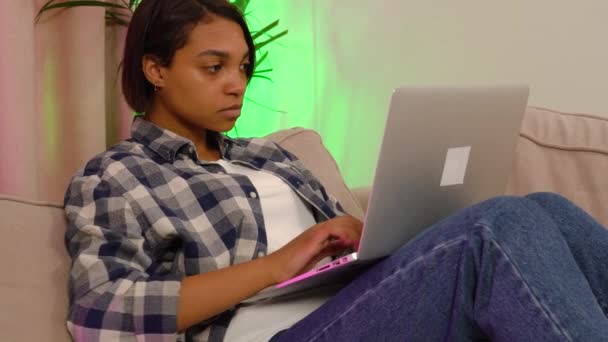 Mladá žena ležící doma na gauči pracuje nebo studuje online. — Stock video