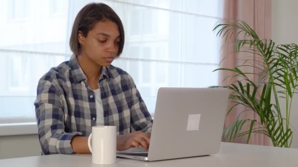 Młoda kobieta siedzi przy biurku komputera, korzystając z laptopa pracującego online w domu. — Wideo stockowe