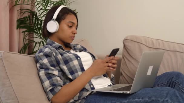 Γυναίκα ξαπλωμένη ακούγοντας μουσική με ακουστικά με ένα τηλέφωνο στα χέρια της. — Αρχείο Βίντεο