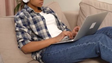 İnternette çalışan bir kadın büyük beyaz kulaklıklarla müzik dinliyor..