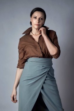 Stüdyoda poz veren şık bir esmer. Kısa saçlı. Gri arkaplan.