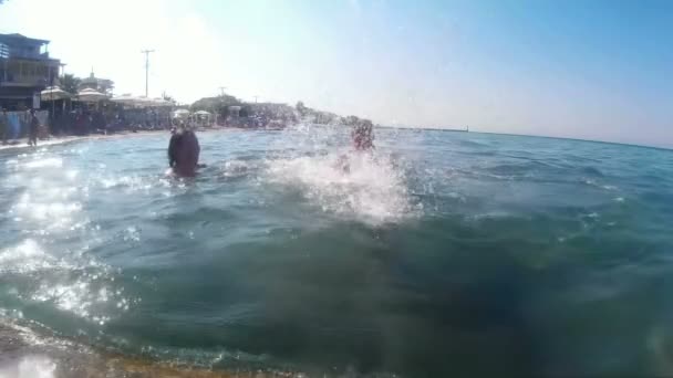Szórakozás a tengeren - a férfi és a nő fröccsenő víz — Stock videók