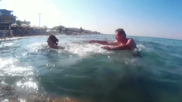 Zábava na moři - muž a žena ve vodě stříkající — Stock video