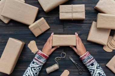 Kazakta bir kadının elleri Noel hediye kutusunu örterek Kraft kağıdıyla süslüyor.