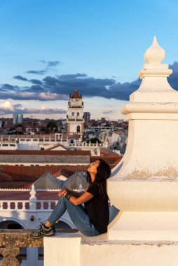 Sucre, Bolivya 'nın çatısından arka planda Sucre ve çan kulesinin manzarasıyla rahatlayan bir kadın.