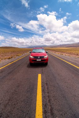 Atacama Çölü, Şili 'de bulutlu bir günde asfalt yolda giden kırmızı araba.