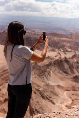 Şili 'nin Atacama Çölü' nde bulutlu bir günde kayalık oluşumların fotoğraflarını çeken isimsiz kadın gezgin.