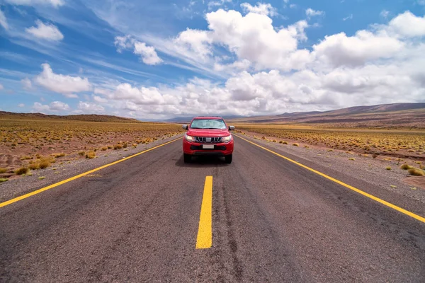 Atacama Çölü, Şili 'de bulutlu bir günde asfalt yolda giden kırmızı araba.