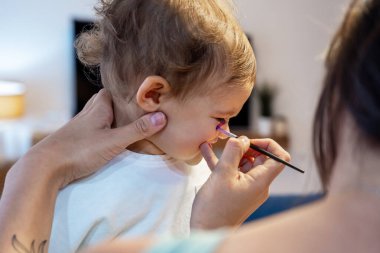 Anne yeni yürümeye başlayan renkli Cadılar Bayramı Hindistanı makyajına başvuruyor.