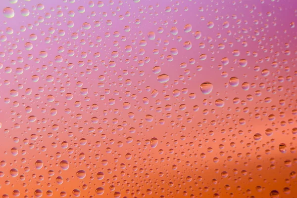 Nahaufnahme von Wassertropfen auf einem Glas. Regenbogen Hintergrund, bunte abstrakte Muster. — Stockfoto