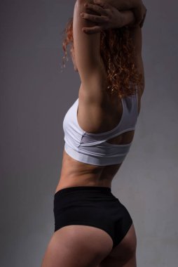 Kusursuz vücut kasları olan atletik kadın sporcunun stüdyo portresi. Gri arkaplanda stüdyo resmi.