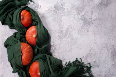 Sonbahar durgun kırmızı balkabakları eski ahşap bir kutuda yeşil bir eşarp içinde uzanır, arka planda eski ahşap sepetli küçük balkabakları ile karanlık bir arka planda. Sığ noktalı Macro.