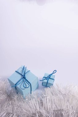 Beyaz arka planda köknar ağacı konileri olan mavi Noel hediyeleri. Beyaz arka planda izole edilmiş beyaz kurdeleli dikey çekim hediye kutusu. Kırpma yolu dahil.