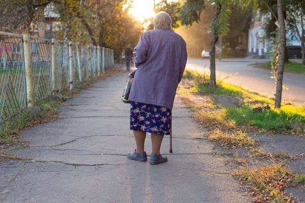 スティックとラメと80歳くらいのおばあちゃんが街の遊歩道を歩いていると — ストック写真