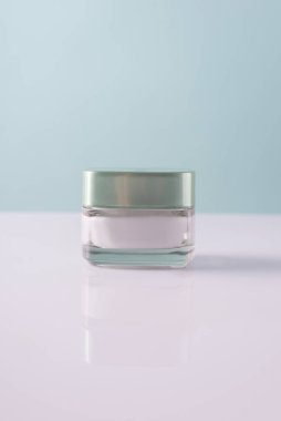 Beyaz-mavi arka planda, kozmetik beyaz krem konteynırı, minimalist.