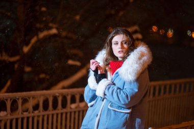 Kışın gece köprüde poz veren kız model. Kışlık kot ceketli güzel genç kız..