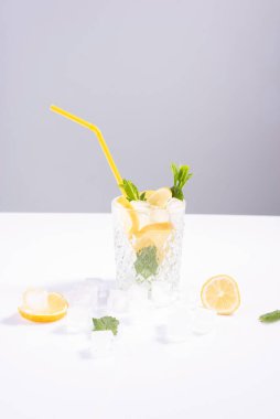 Minimalist ferahlatıcı yaz içeceği kokteyli. Beyaz arka planda limon, nane ve buz küpleri..