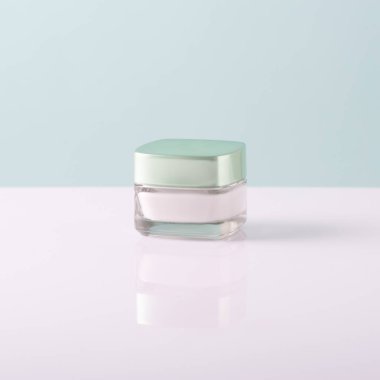 Beyaz-mavi arka planda cam bir kapta yüz kremi..